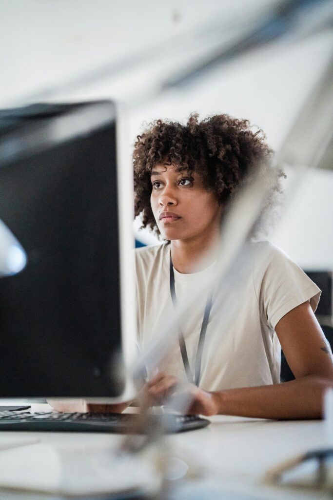 Young woman concentrating on a computer screen in a modern office setting.